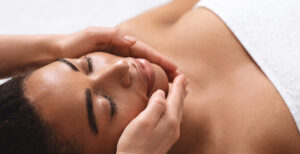 Closeup of therapist hands making facial massage for black lady