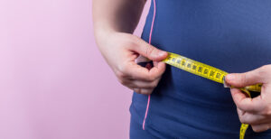 A woman measuring her waist while in sportswear.
