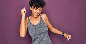 A woman joyfully dancing while in sportswear.