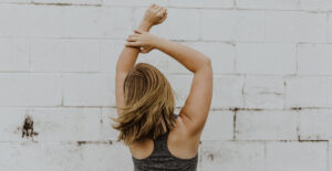 A woman facing away with her arms above her head.