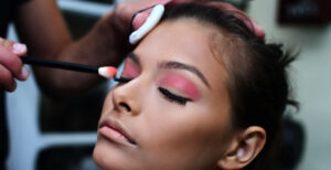someone applying makeup onto a woman with pink eyeshadow