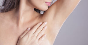 A woman lifting up her arm and touching her armpit area