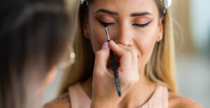 woman with her eyes closed and getting her makeup done by a professional makeup artist
